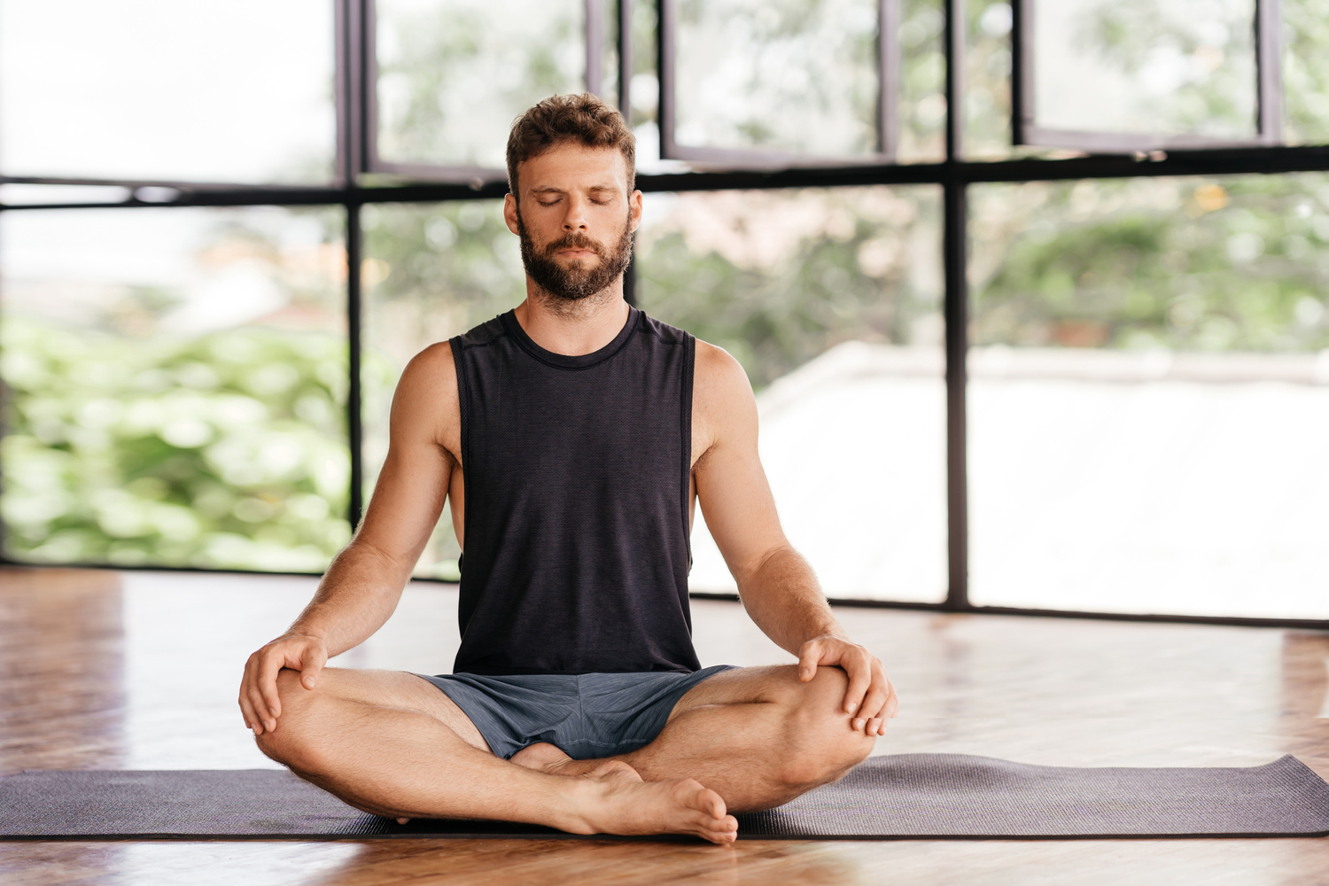 Yoga men workout in studio in front of a window